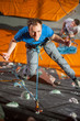 © anatoliy_gleb - Man with climbing equipment hanging on a rope an indoor rock-climbing wall, giving the thumb up, view from above