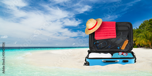 Packed suitcase on tropical...