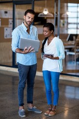 Wall Mural - Young man and woman discuss using digital tablet and laptop 