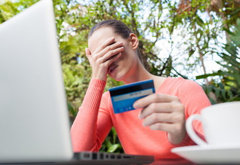 Financial problems concept. Depressed woman holding a credit card.