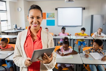 miced race teacher posing in front of class with tablet pc