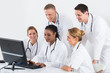© Andrey Popov - Group Of Doctors Looking At Computer At Desk