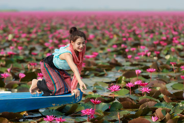 Beautiful girl sitting in boat in the lotus field