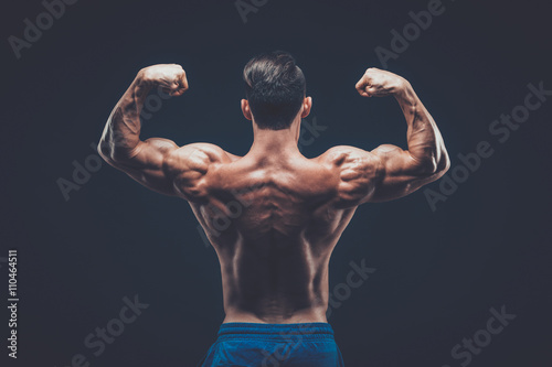 Homme musclé posant en studio sombre sur fond noir. Poster Mural XXL