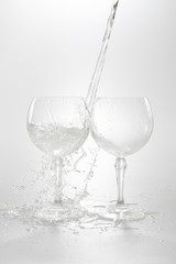 Water is pouring in two wine glasses