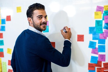 Aufkleber - Young man smiling at camera while writing on white board