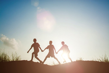 Wall Mural - Silhouette of children playing in the park sunset time