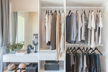 white wardrobe with shirts and pants hanging