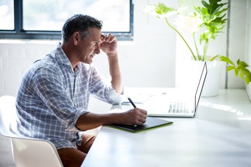 Serious man working at desk with laptop