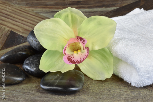 Naklejka na drzwi Spa still life with hot stones, orchid flower and white towel on wood background.
Health, spa and beauty concept.