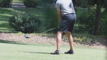 Left Handed Male Golfer Swings At A Golf Ball On A Tee With A Driver
