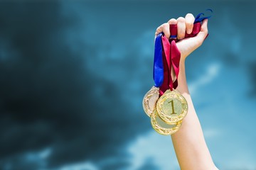 Poster - Composite image of hand holding three medals on white background