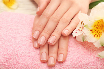 Wall Mural - Spa concept. Woman hands with beautiful manicure and flowers on towel, close up