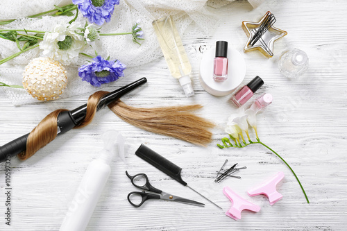 Strand of hair with flowers, barber equipment and tools on light wooden backgrou Fototapete