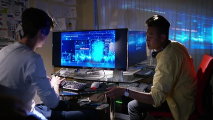  Young men working in front of computers with headphones on