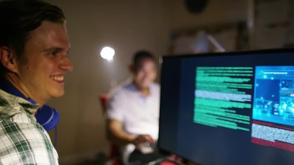 Young men working in front of computers with headphones on