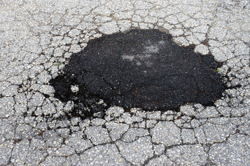 cracked asphalt road surface and repair patch