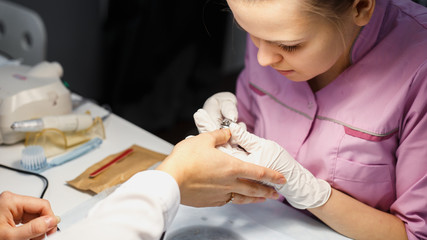 Manicure care procedure, Close-up photo Of Beautician Hand Painting Nails Of Woman In Salon