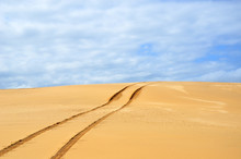 Vehicle Tracks On A Remote, Deserted Sand Dune Disappearing Over The Horizon.