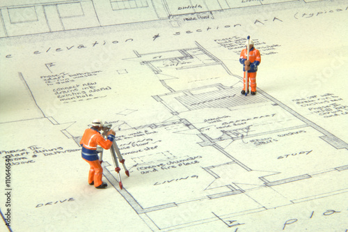 Fotografie, Obraz Two miniature figures in high-vis uniform with a theodolite survey a house bluep