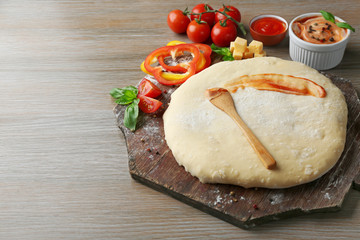 Canvas Print - Fresh dough prepared for pizza with tomatoes and sliced pepper on a wooden board, close up