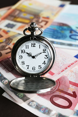 Poster - Time is money concept with pocket watch and euros bills closeup