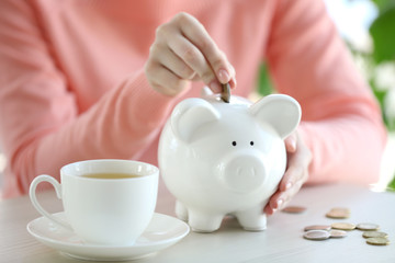 Woman putting money in piggy bank