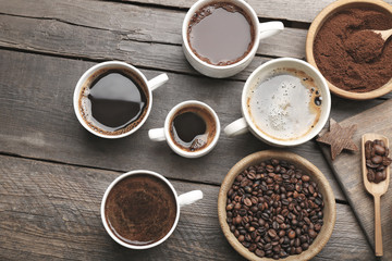 Wall Mural - Cups of coffee with spices on wooden table, top view