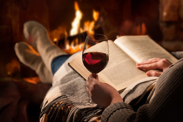 Woman reads book near fireplace