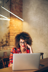 Wall Mural - Young woman sitting at cafe working on laptop
