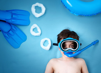 Child lying on blue blanket with swimming mask and flippers