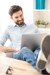 Wall Mural - Attractive businessman is working on laptop with joy