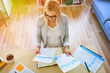 © baranq - High angle view of young businesswoman working from home at desk