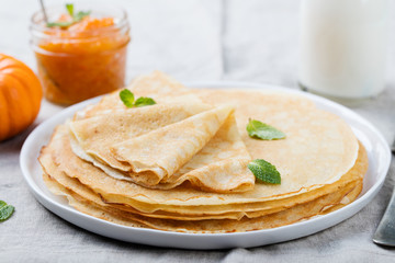 Wall Mural - Thin crepes or pancakes with butter, honey and sour cream on a rustic textile background