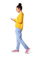 smiling young woman walking and looking at mobile phone