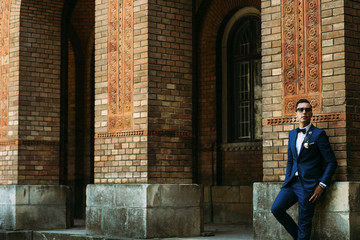 Wall Mural - Stylish groom next to the wall in the wedding day