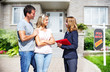 © grinny - Real Estate agent woman with clients near new house.