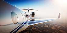 Photo Of White Luxury Generic Design Private Jet Flying In Blue Sky At Sunset.Uninhabited Desert Mountains Background.Business Travel Picture.Horizontal,Film Effect. 3D Rendering.