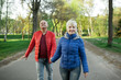 © goami - happy seniors couple hold hands and walk;