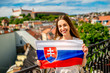 Young female tourist holding slovak flag in Bratislava city. Promoting tourism in Slovakia