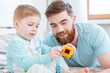 © Drobot Dean - Dad and son playing with toys on bed