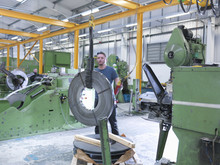 Worker Loading Rolls Of Metal Into Stamping Machine In Engineering Factory
