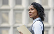 © Connect Images - Portrait of young business woman holding paper work, looking away, side view