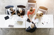© Connect Images - Overhead view of businessmen and women shaking hands with client at desk in office