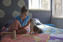 Woman Sitting On Bed Petting Dog