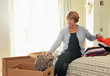 © Connect Images - Senior woman in bedroom packing clothes into boxes