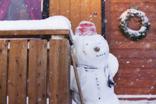Snowman Standing Against Wooden Fence