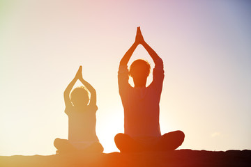 Wall Mural - father and son doing yoga at sunset sky