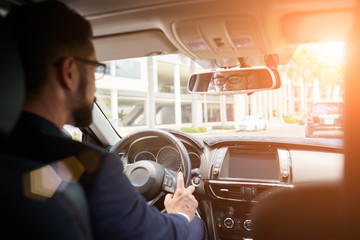 Young businessman driving to work, view over the shoulder