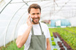 Portrait of an attractive farmer in a greenhouse using mobile